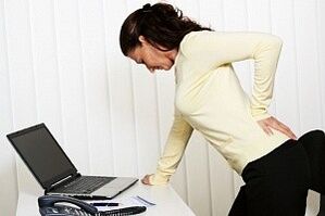 una mujer tiene dolor de espalda en la región lumbar